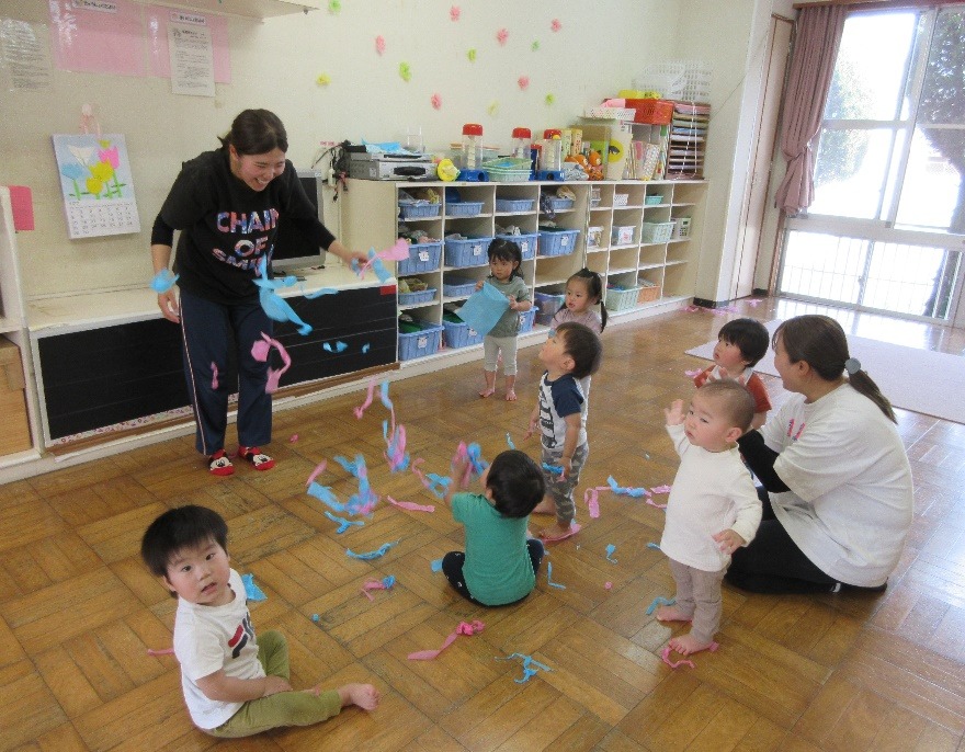 写真：先生と一緒にお花紙で遊んでいる様子